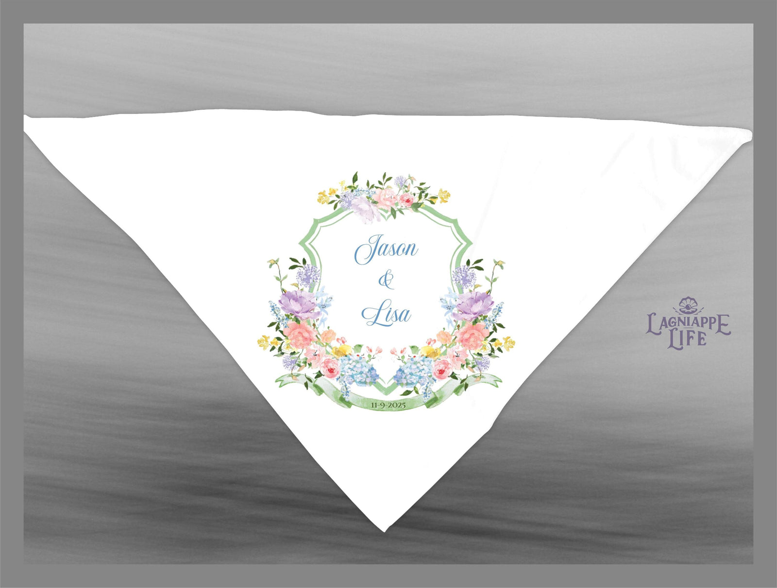 May include: A white wedding handkerchief with a green, blue, and pink floral design. The handkerchief has a green border with the words 'Jason & Lisa' and the date '11.19.2016' in blue text. The handkerchief has a small logo in the bottom right corner that says 'Lagniappe Life'.