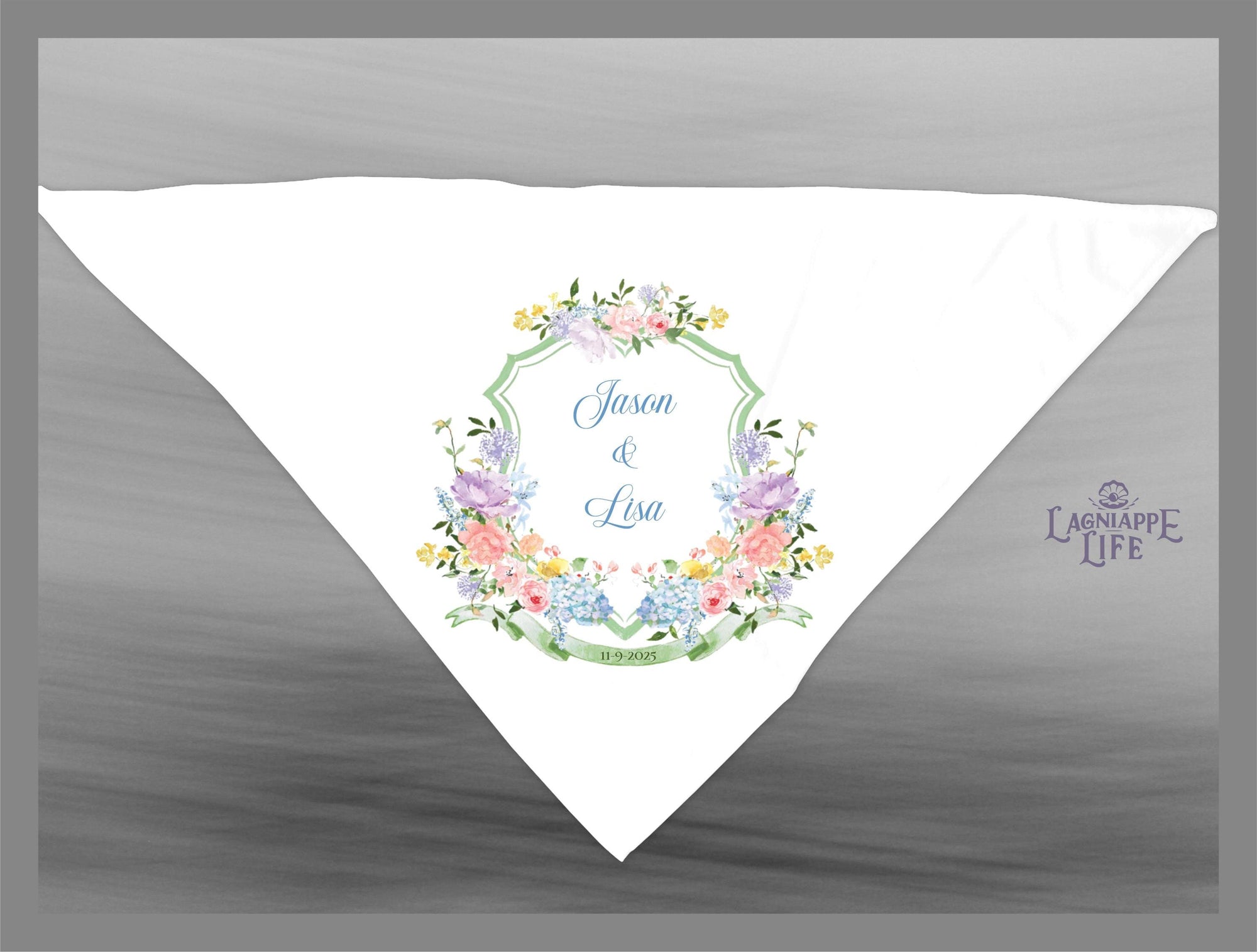 May include: A white wedding handkerchief with a green, blue, and pink floral design. The handkerchief has a green border with the words &#39;Jason & Lisa&#39; and the date &#39;11.19.2016&#39; in blue text. The handkerchief has a small logo in the bottom right corner that says &#39;Lagniappe Life&#39;.