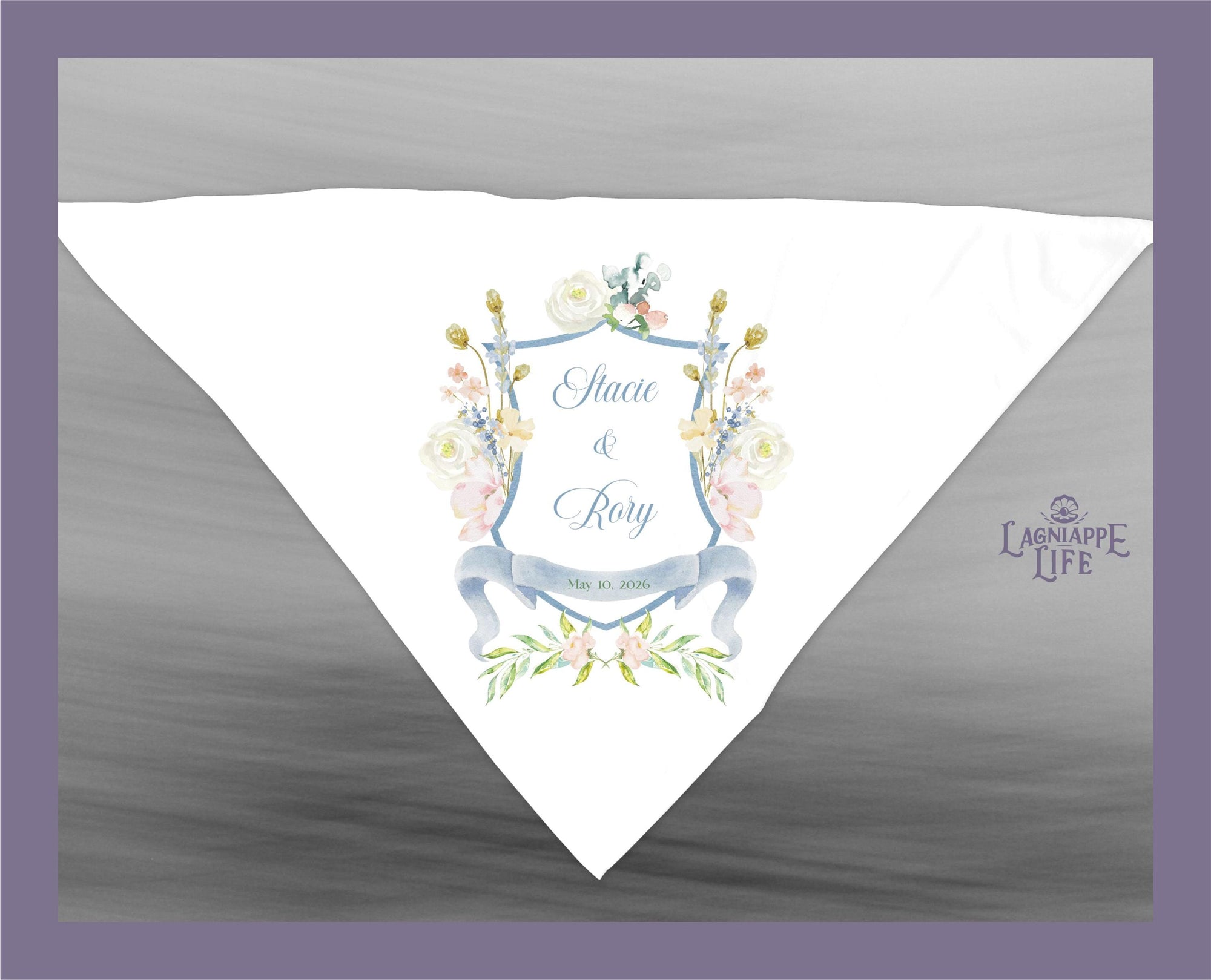 May include: A white wedding handkerchief with a blue and white floral design. The handkerchief has a blue shield with the text &#39;Stacie & Rory&#39; and &#39;May 10, 2020&#39; in the center. The shield is surrounded by a floral wreath. The text &#39;LAGNIAPPE LIFE&#39; is in the lower right corner of the handkerchief.
