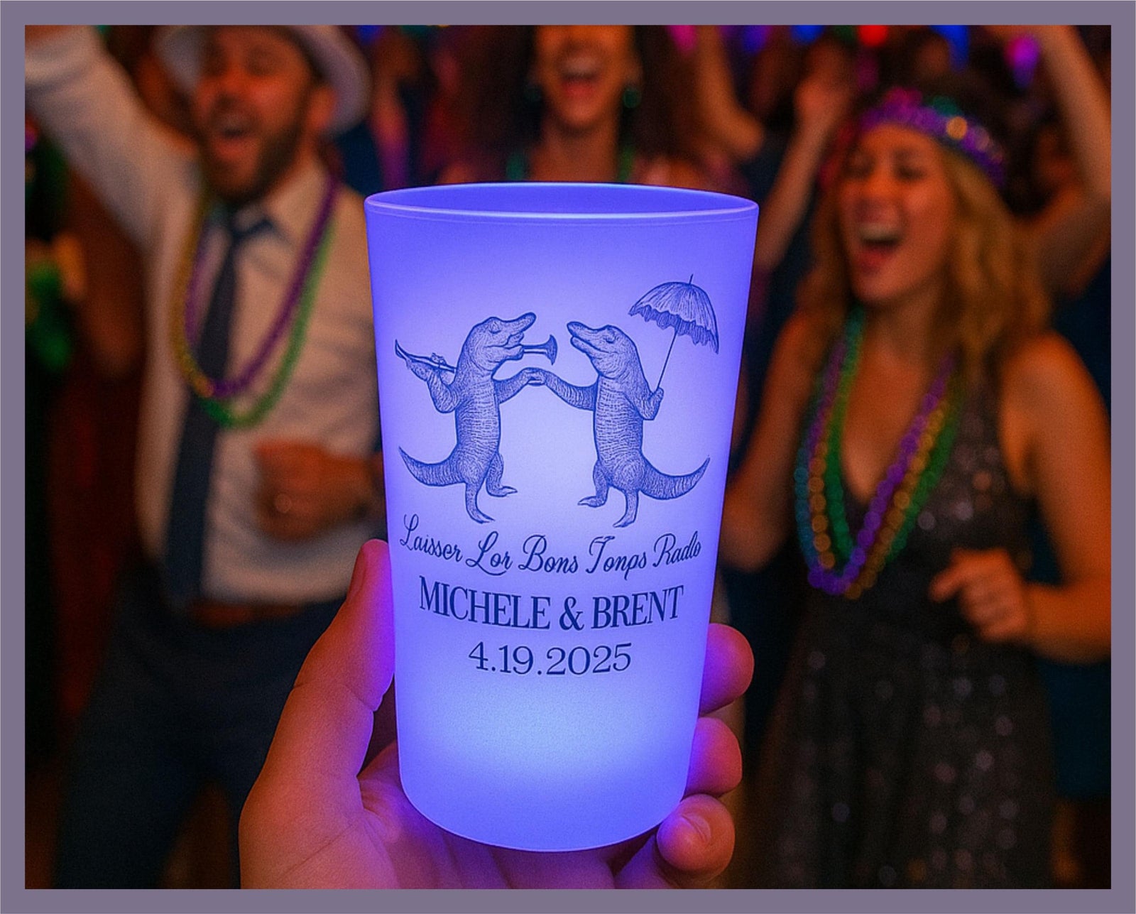 A hand holding a blue cup with a design of two dancing alligators, surrounded by a lively party scene with people dancing and celebrating.