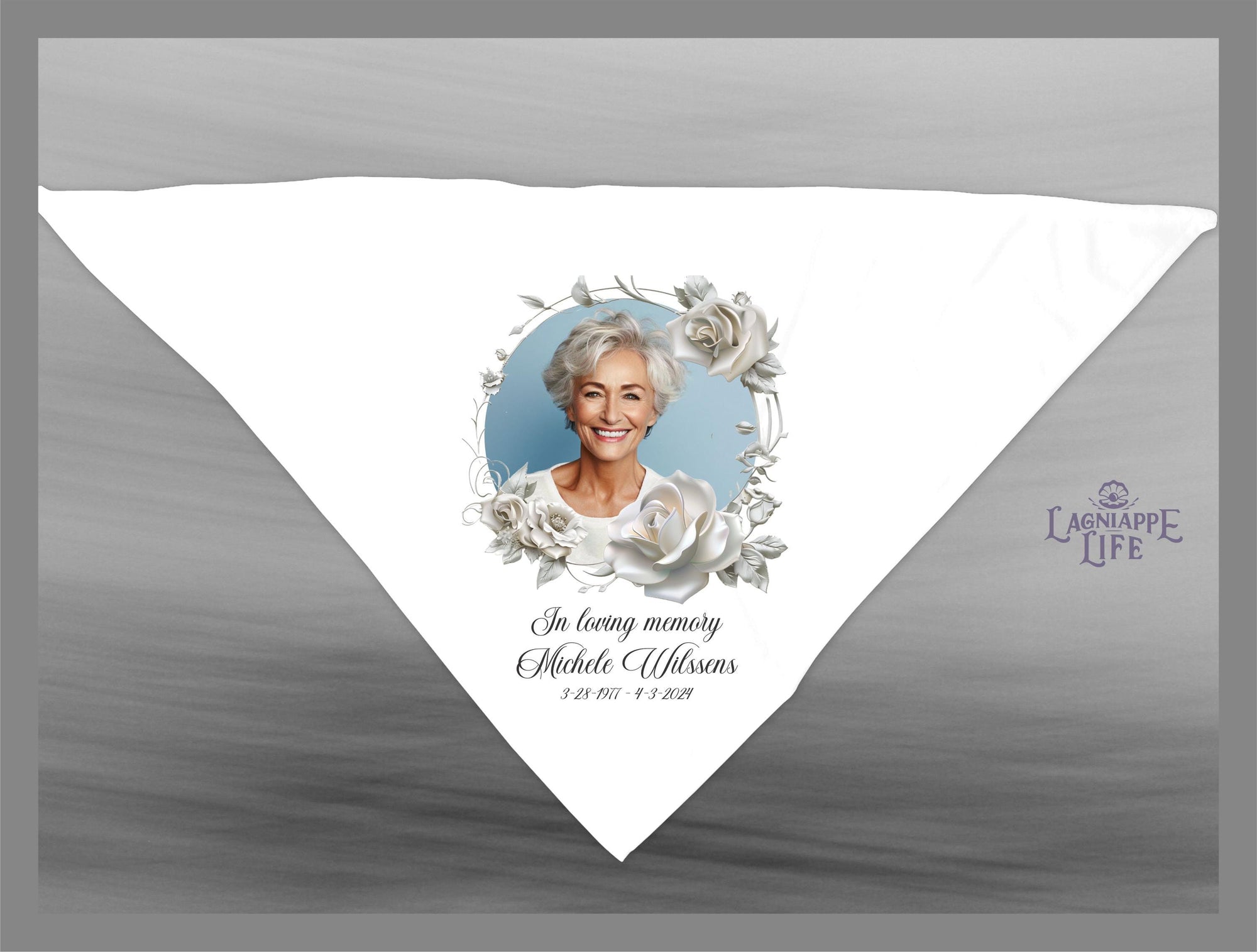 May include: A white triangular fabric with a floral design and a photo of a woman. The text reads &#39;In loving memory Michele Ulfssons 3-23-1957 - 3-2-2019&#39;.