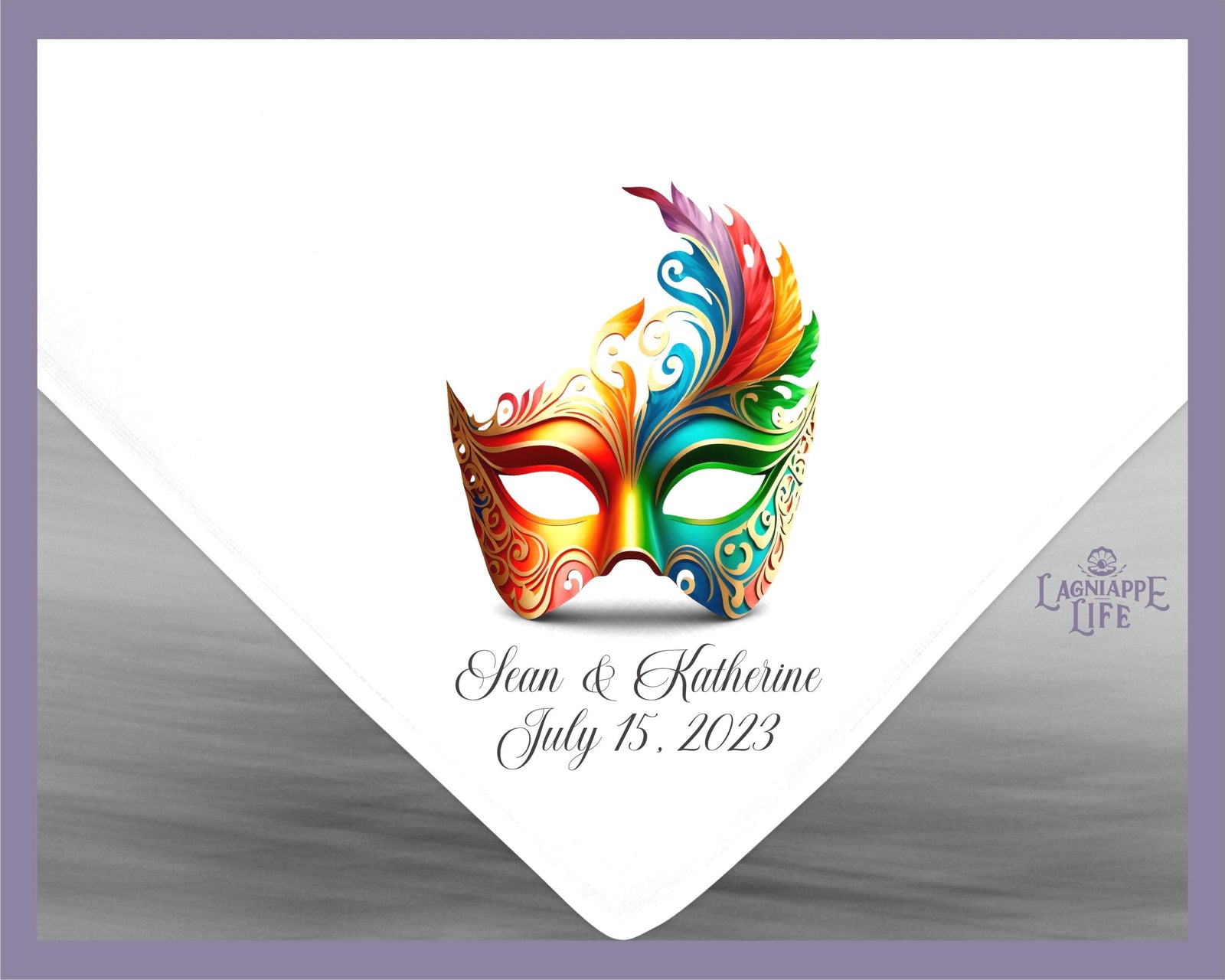 May include: A white wedding napkin with a colorful masquerade mask design. The text below the mask reads 'Sean & Katherine July 15, 2023'.