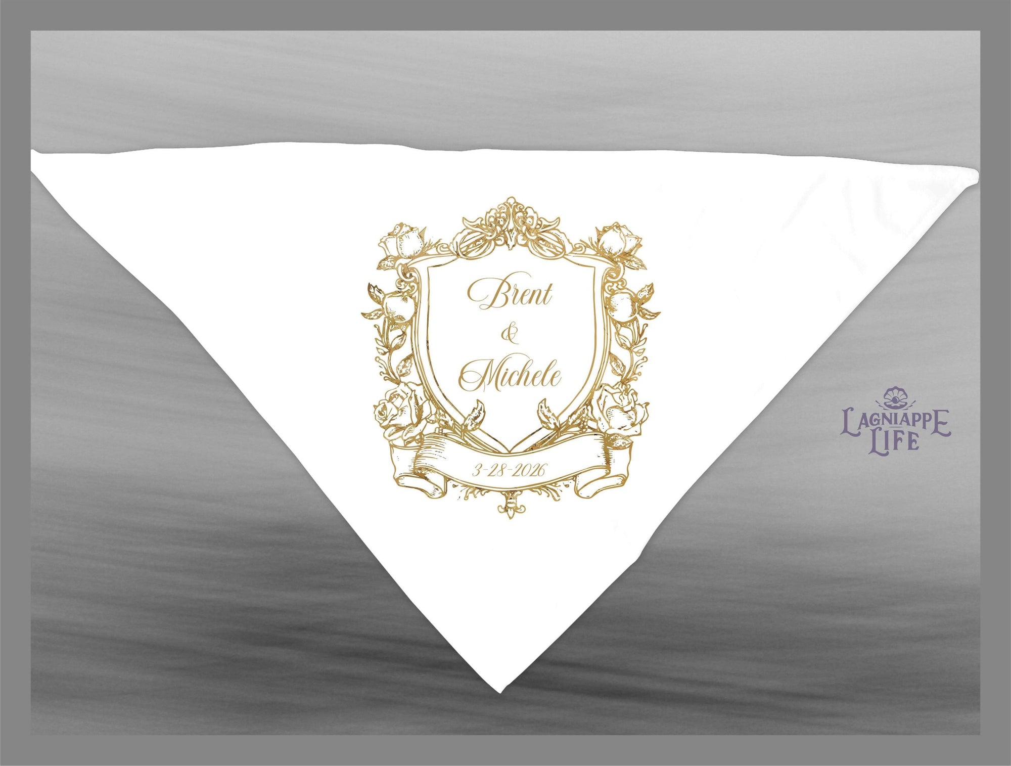 May include: A white wedding favor with a gold crest design. The crest features a shield with the names &#39;Brent & Michele&#39; and the date &#39;3.18.2018&#39;. The crest is surrounded by floral designs and a banner. The text &#39;Lagniappe Life&#39; is in the lower right corner of the favor.